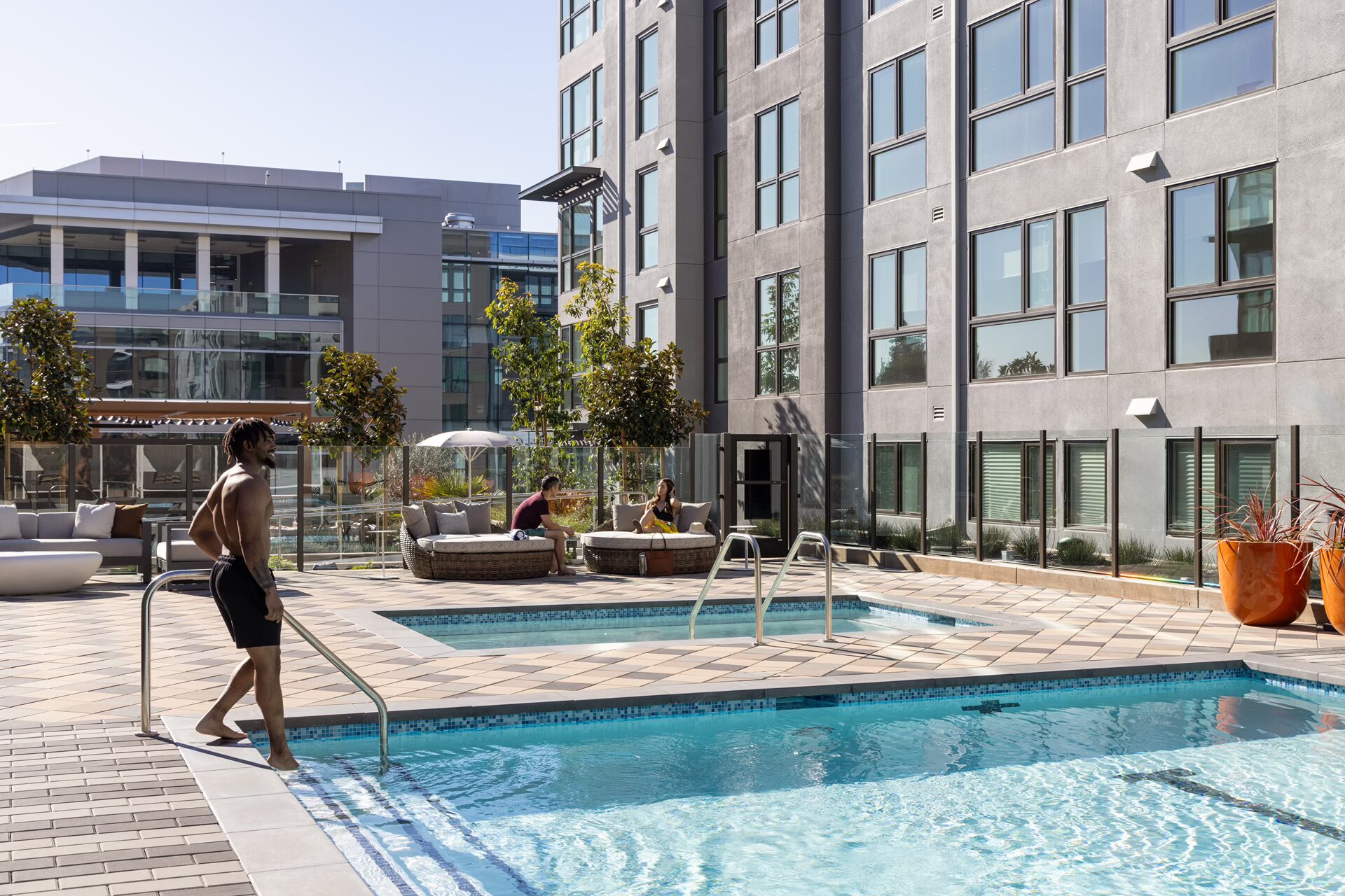 Mountain View, CA, Luxury Studio Apartments - Avelle - Resort Style Courtyard Pool With Spa, Lounge Seating, Sun Umbrellas, And Modern Apartment Building Views.